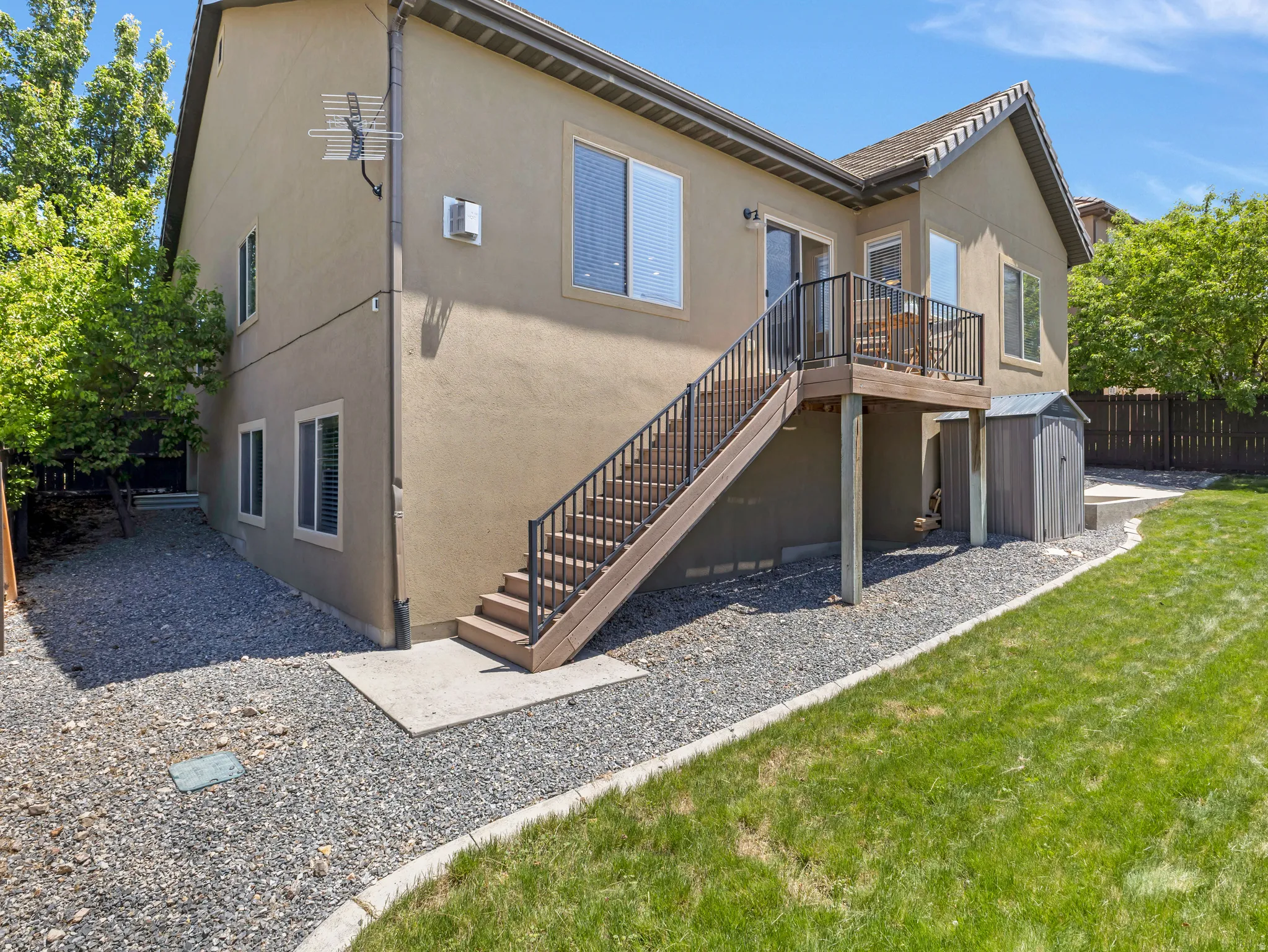 Rear exterior featuring a second-story deck with dark railing, composite stairs, and a stucco finish