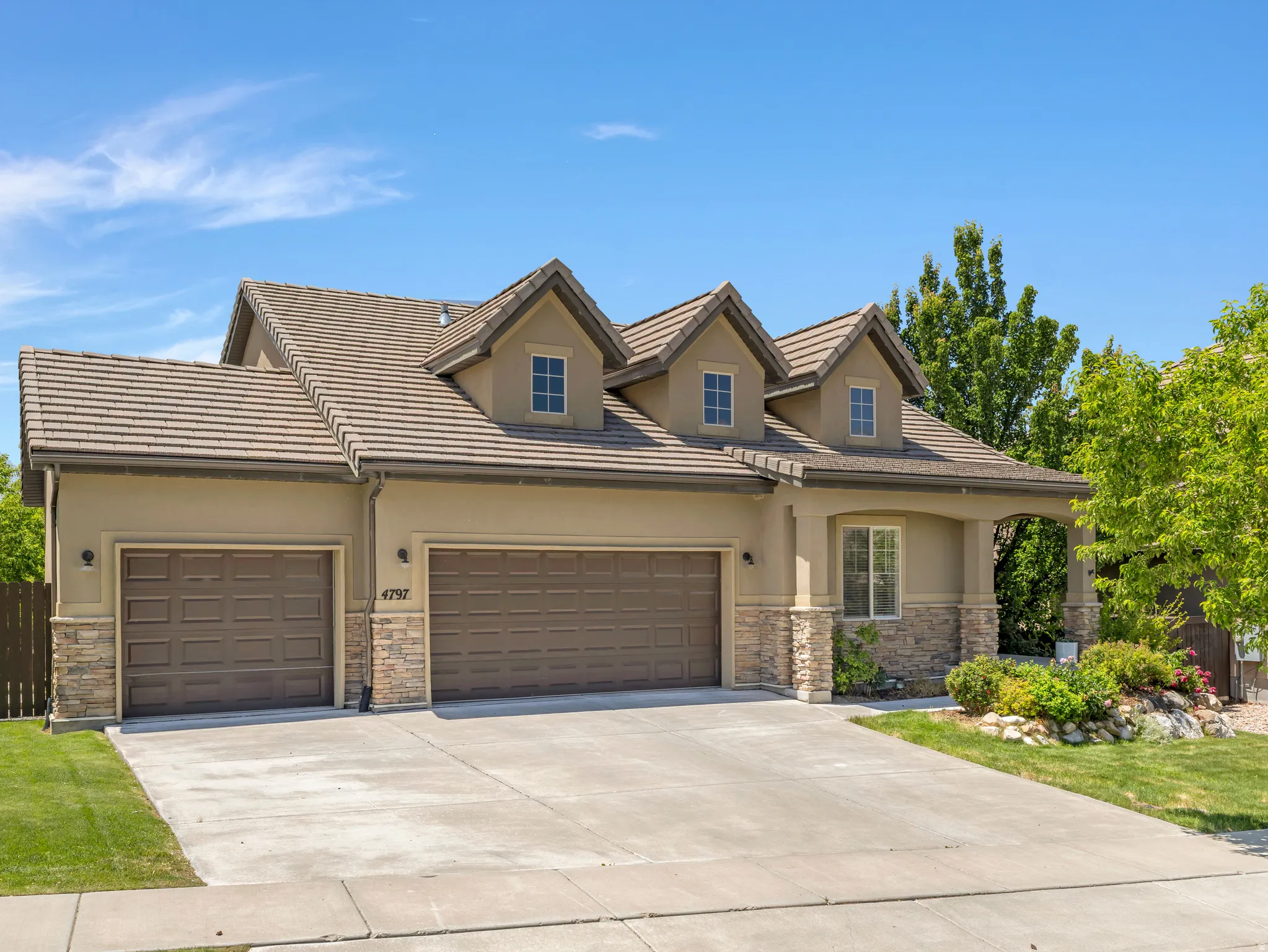 Stucco exterior with stone accents and a multi-gabled tiled roof