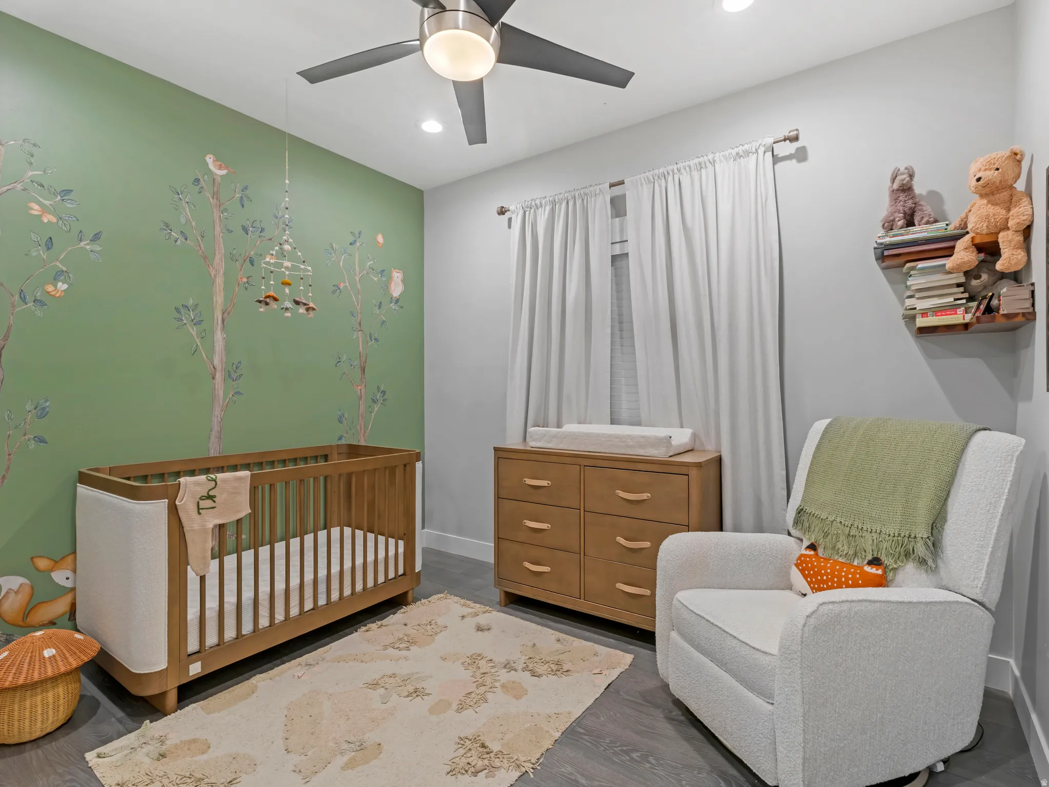Green accent wall with tree-themed mural