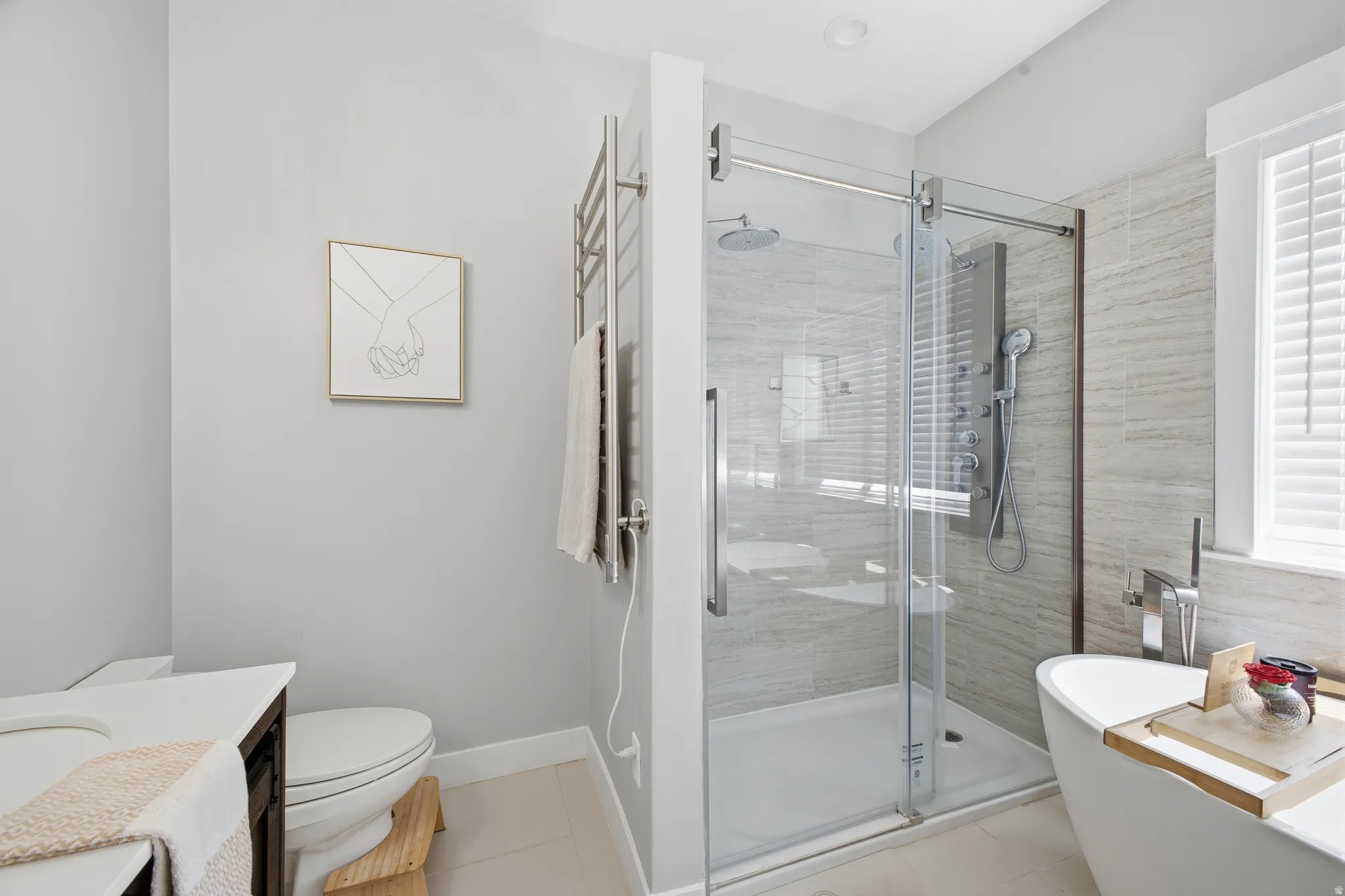 Contemporary bathroom featuring a frameless glass shower enclosure with a rain showerhead and body jets, a freestanding soaking tub, and a white vanity with an undermount sink