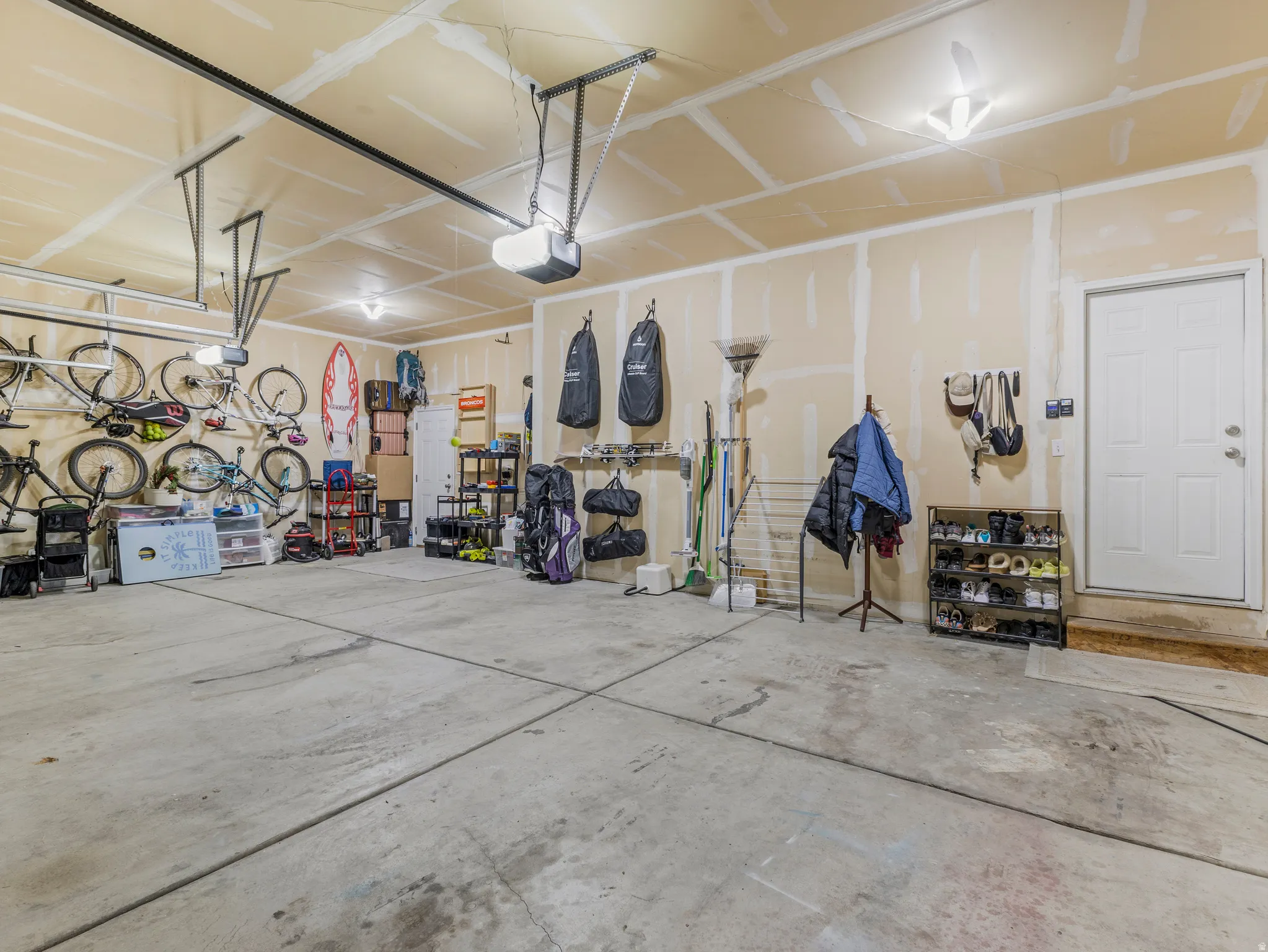 Spacious garage featuring a concrete floor, exposed drywall walls, overhead lighting, and an overhead garage door opener