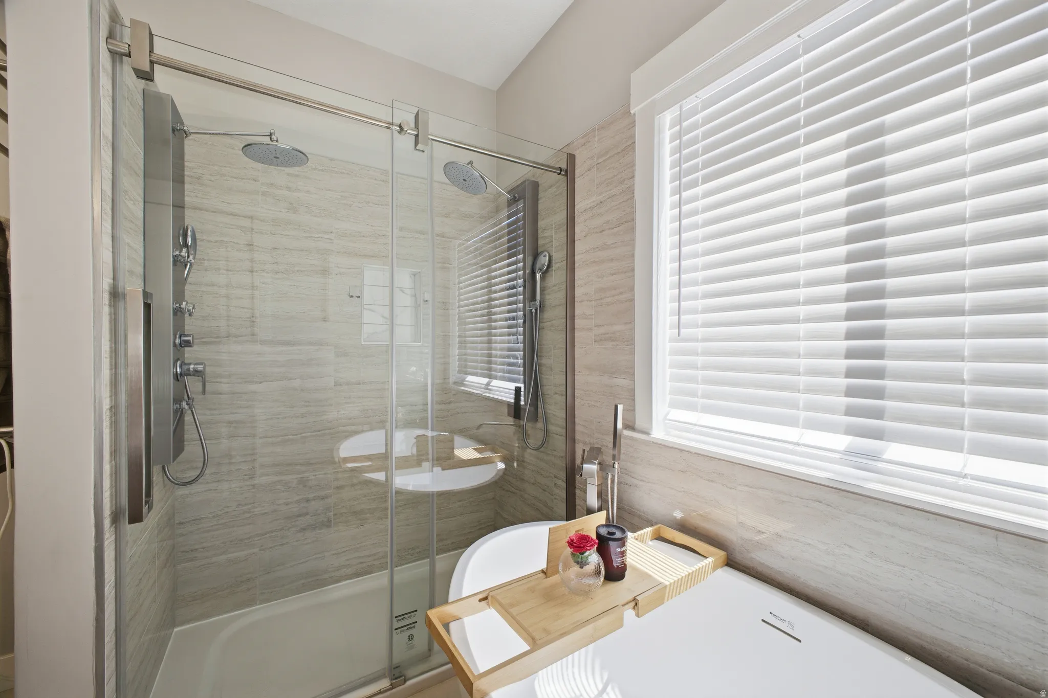 Modern bathroom featuring a frameless glass shower enclosure with dual rainfall showerheads and a multi-function shower panel