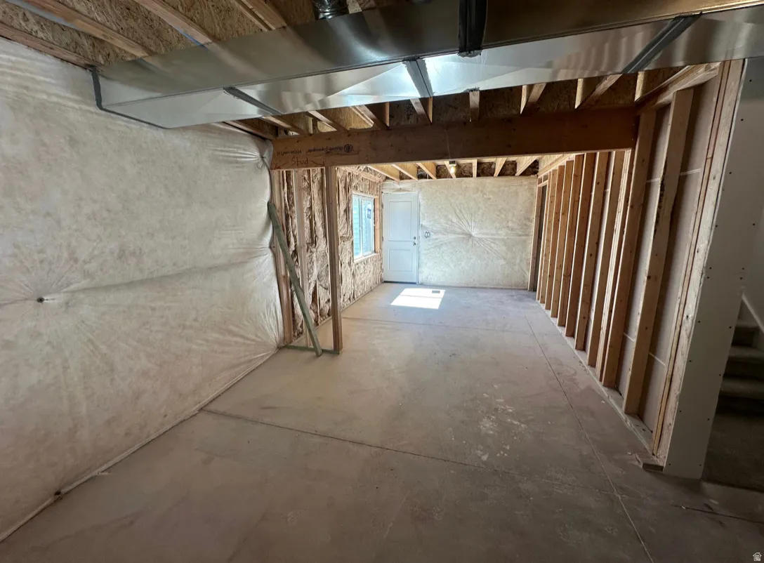 Unfinished basement space featuring exposed wood framing, concrete flooring, and visible insulation