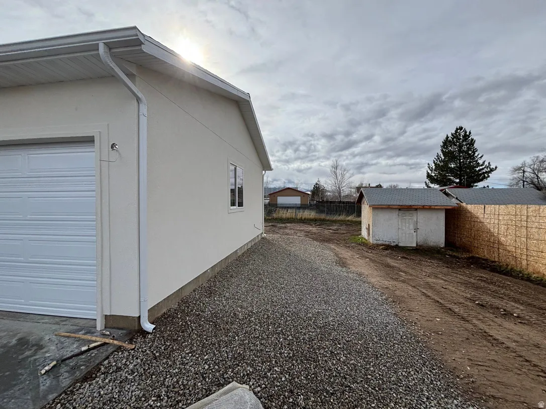 New construction exterior featuring a white garage door, light-colored stucco siding, and white gutters