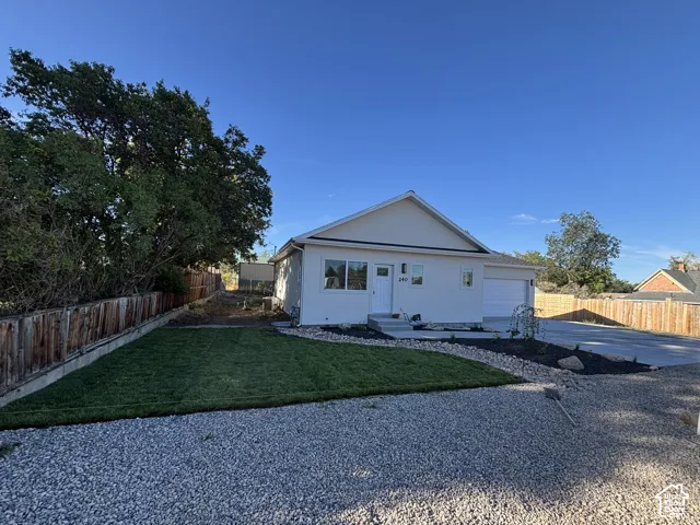 Newly installed sod, mature trees, gravel driveway, attached garage, and light-toned exterior siding