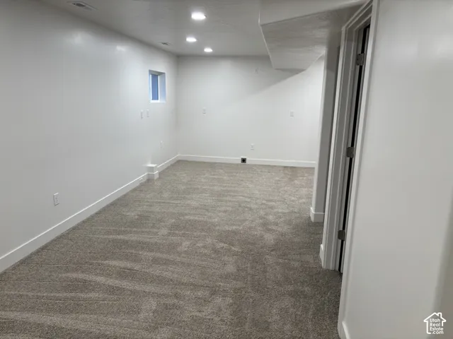 Recessed lighting, neutral-toned carpeting, white walls, and a small window