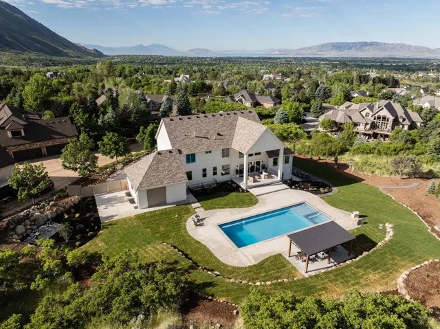 Expansive property featuring a white exterior, a large swimming pool, a concrete pool deck, and a detached pergola structure