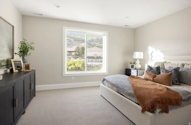 Bright bedroom featuring a large window, recessed lighting, neutral wall tones, and plush carpeting