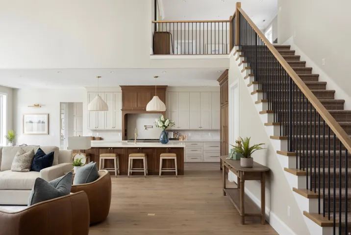 Open-concept living space featuring a grand staircase with wood-finish handrails and black metal balusters