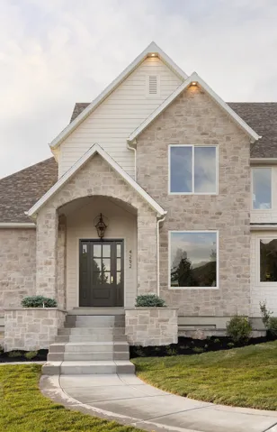 Stone and siding exterior featuring an arched entryway