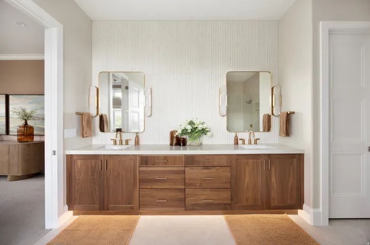 Double vanity featuring wood-finish cabinetry, white countertop, and dual rectangular sinks with brass-tone faucets