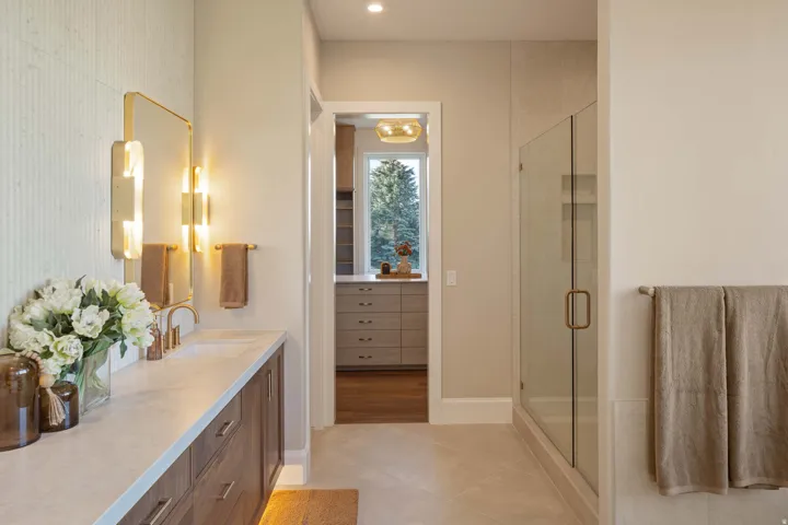 Bathroom vanity with a white countertop and dark wood-finish cabinetry, featuring a mounted rectangular mirror with integrated lighting