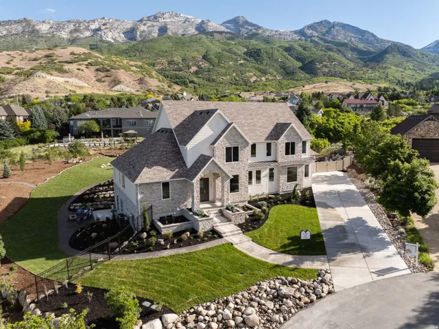 Stone and siding residence featuring a multi-gabled roofline, an integrated two-car garage, and a concrete driveway
