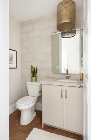 Bathroom featuring hexagonal terracotta tile flooring and a light-toned brick pattern accent wall