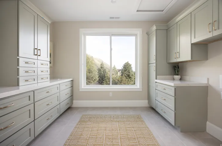 Functional room featuring extensive cabinetry with various drawer and cupboard configurations, light-colored countertops, and a large window