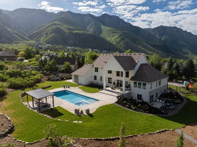 Two-story home with a multi-level roofline, a large rear patio, and a swimming pool with an integrated spa