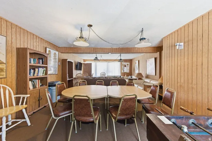 Spacious common area featuring wood-finish paneling, drop ceiling, and multiple pendant light fixtures