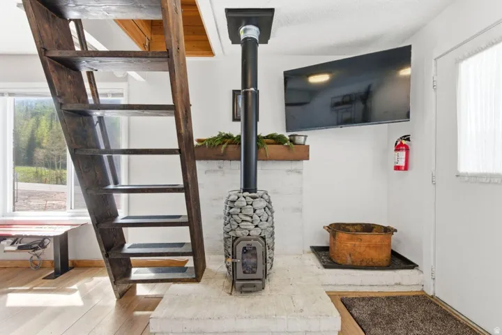 Freestanding wood-burning stove with a stacked stone base and brick hearth