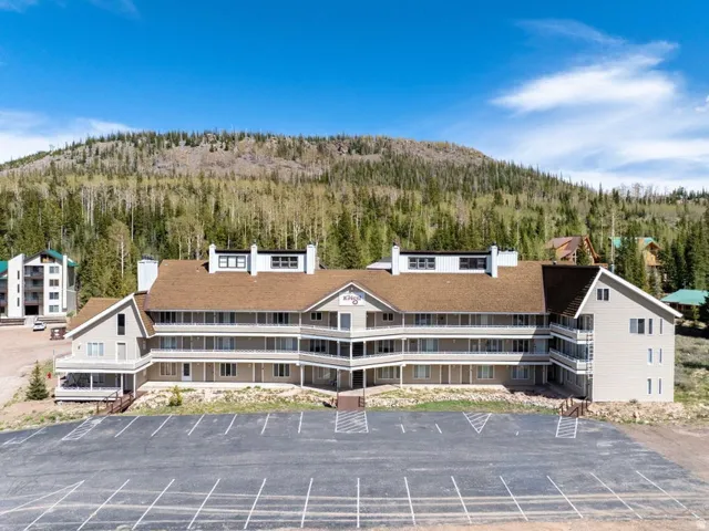 Multi-level building featuring a brown shingle roof, light-toned siding, and multiple private balconies