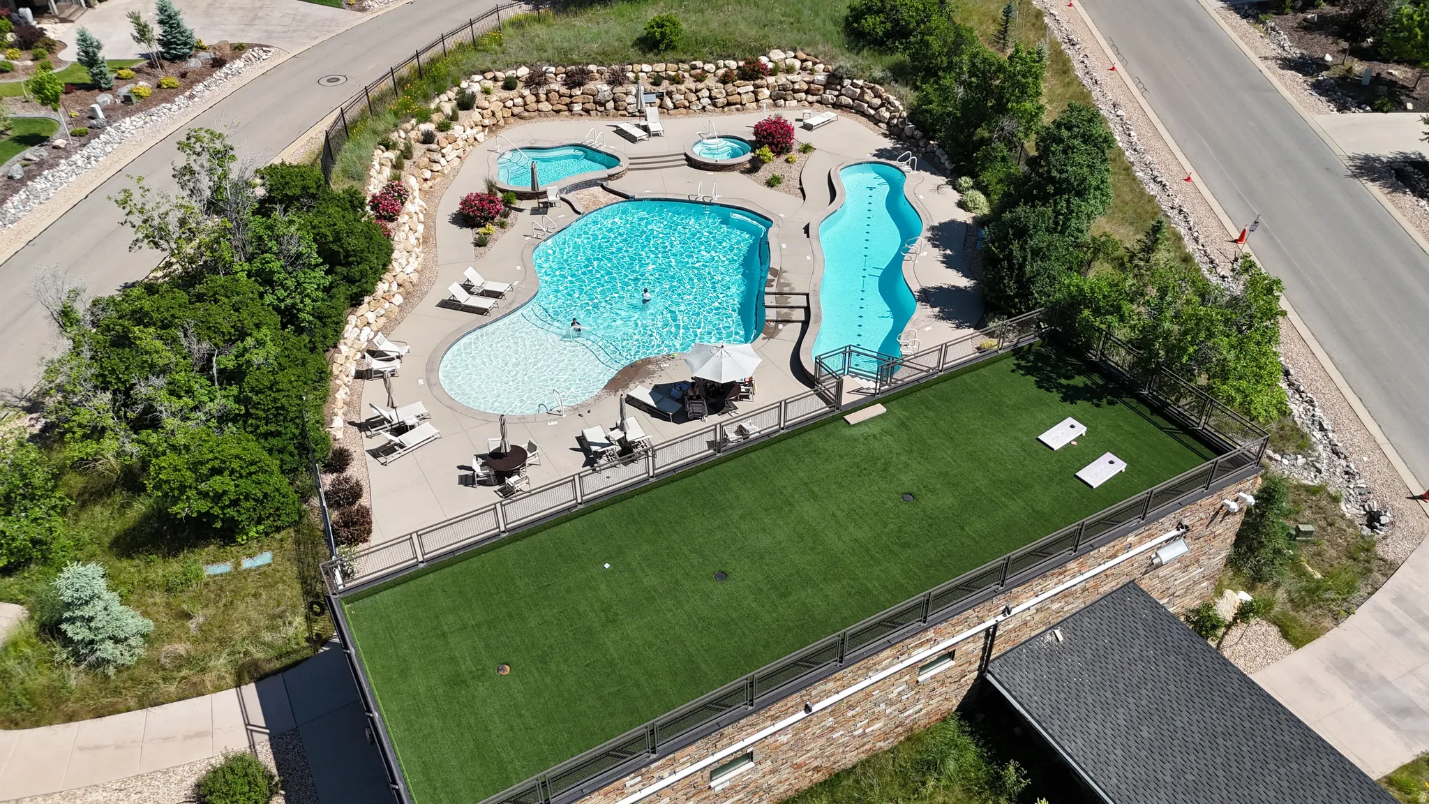 Community recreation area featuring multiple swimming pools, a hot tub, and a spacious artificial turf lawn