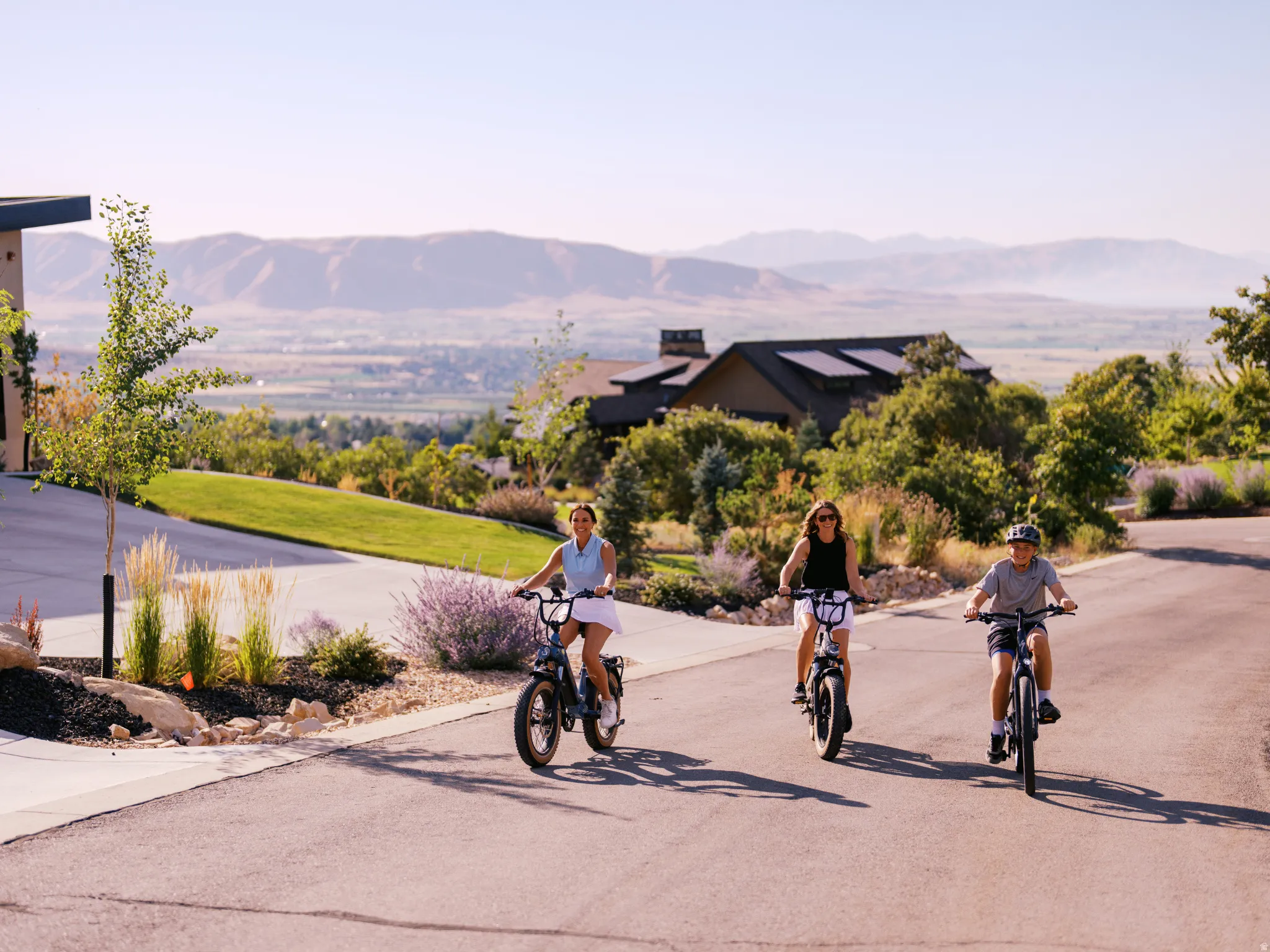 Paved residential street with landscaped verges featuring decorative rocks and plantings