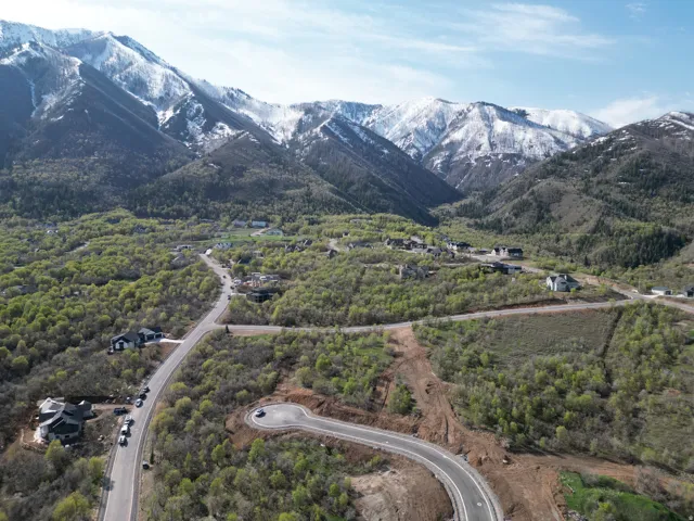 Mountainous terrain featuring snow-capped peaks, verdant hillsides, and established residential structures