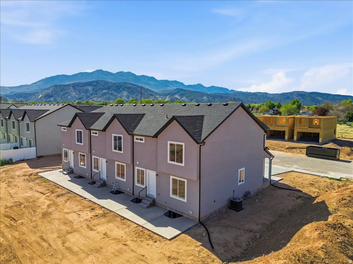 Newly constructed multi-level townhome featuring a neutral stucco exterior and dark shingle roof
