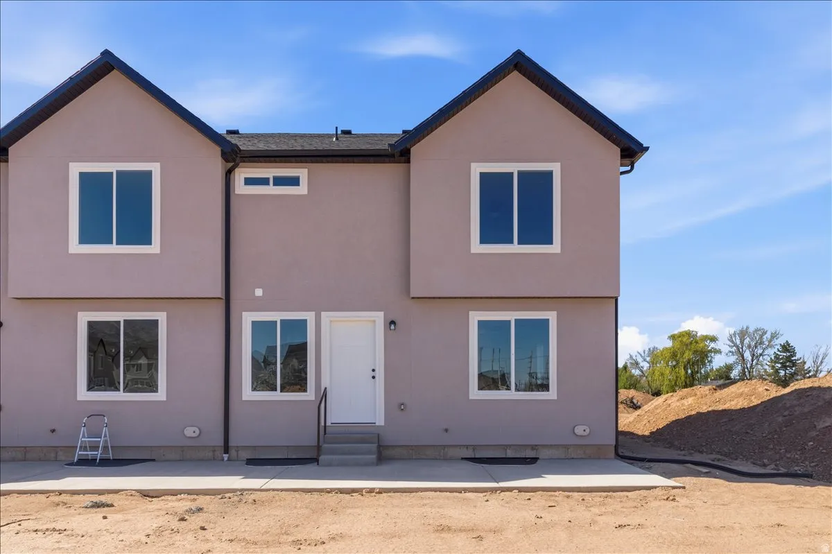 Contemporary townhouse exterior featuring a neutral stucco finish and dark-trimmed gable roofs