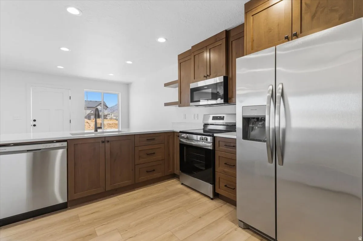 Kitchen featuring stainless steel appliances, wood-finish flooring, white countertops, recessed lighting, and ample cabinetry