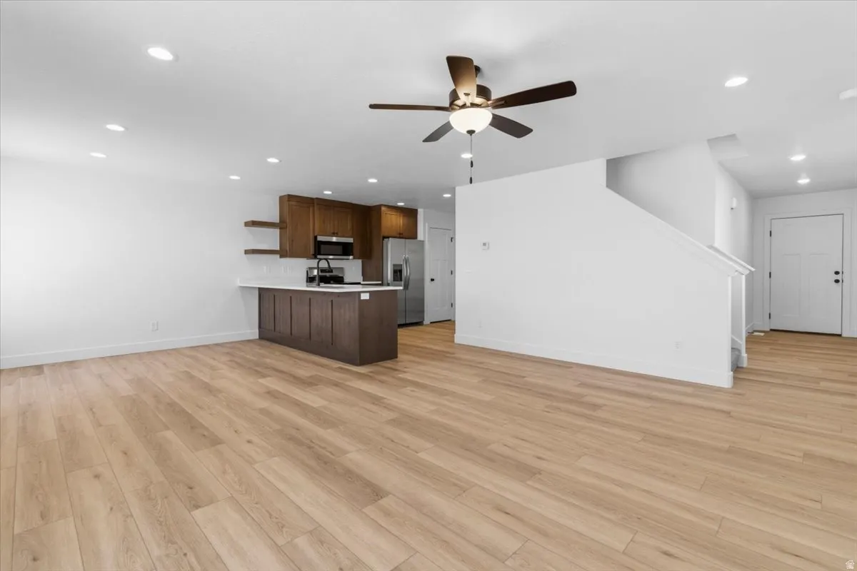 Open-concept living area featuring light wood-finish flooring, recessed lighting, and a contemporary ceiling fan