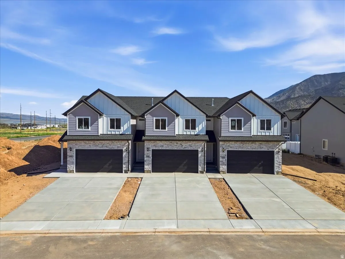 Contemporary townhome-style residences featuring light gray siding, white vertical siding accents, and stone façade detailing
