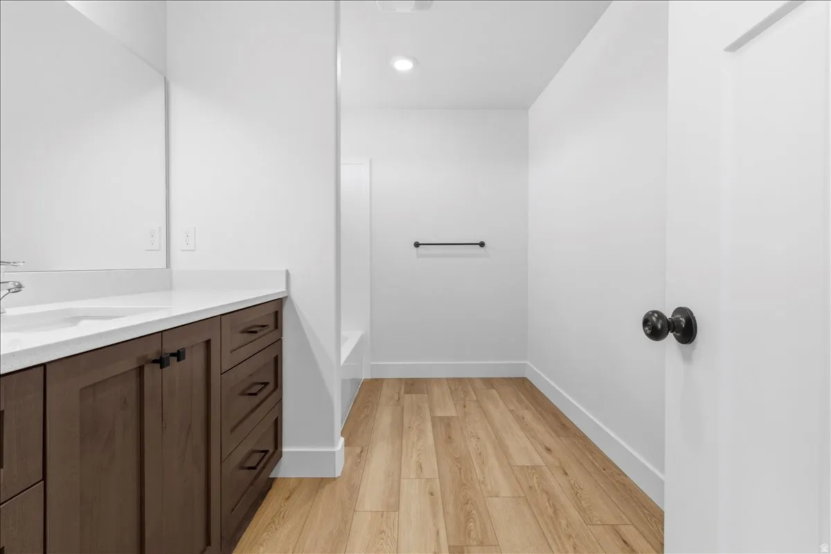 Bathroom vanity featuring a white countertop, undermount sink, and wood-finish cabinetry with dark hardware
