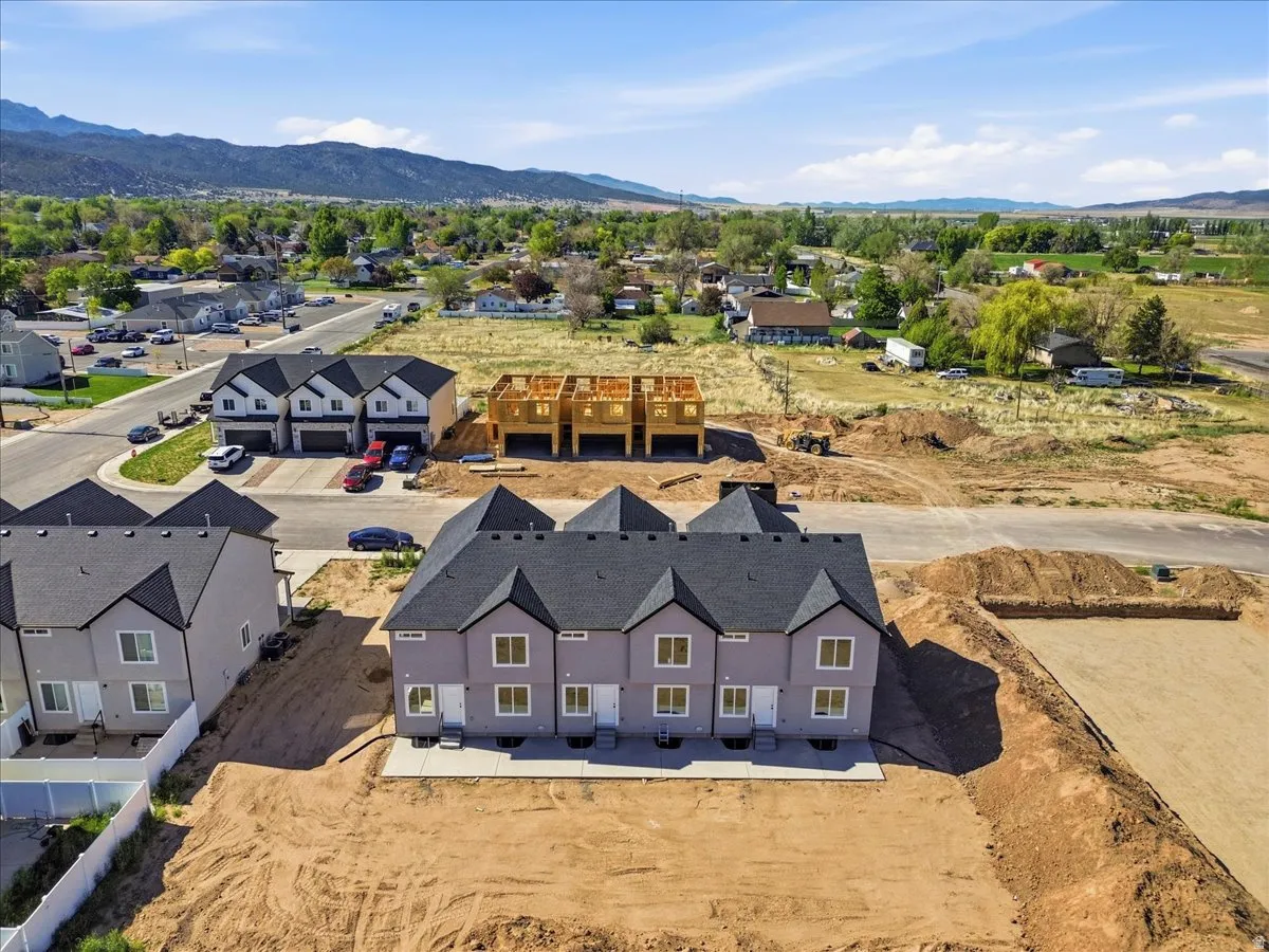 New construction townhomes featuring light gray siding, dark shingle roofs, and white trim windows