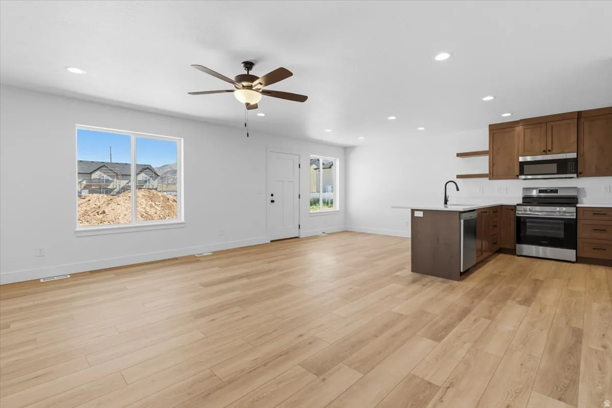Open-concept living space featuring wood-finish flooring, recessed lighting, and a ceiling fan