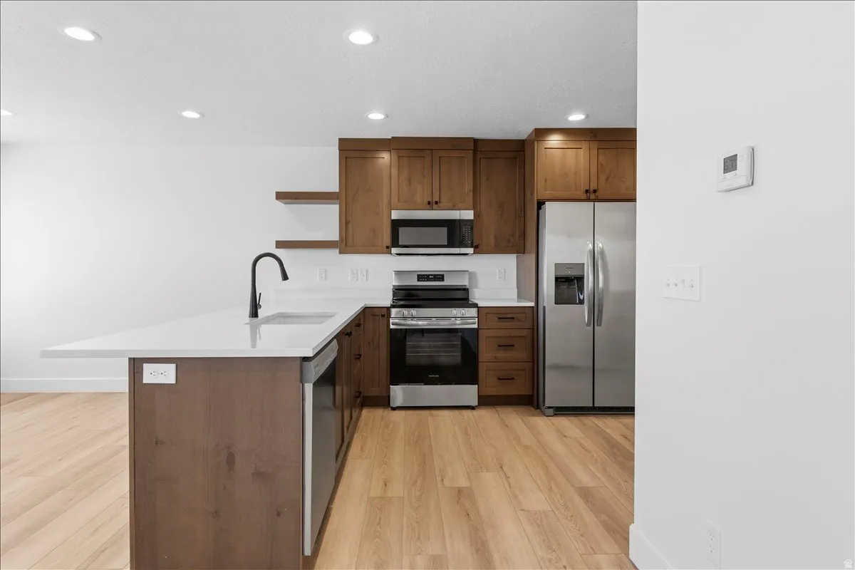 Modern kitchen featuring light wood-finish flooring, white walls, and recessed lighting