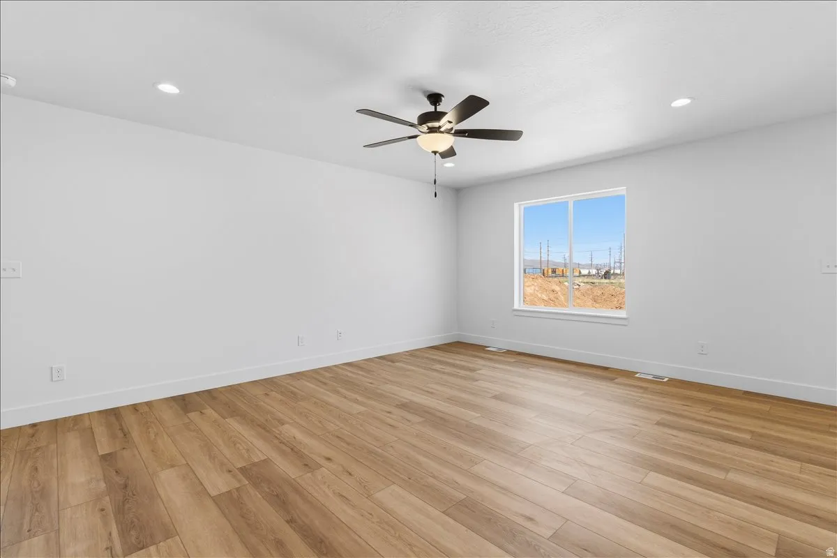 Spacious room featuring wood-finish flooring, white baseboards, and bright white walls