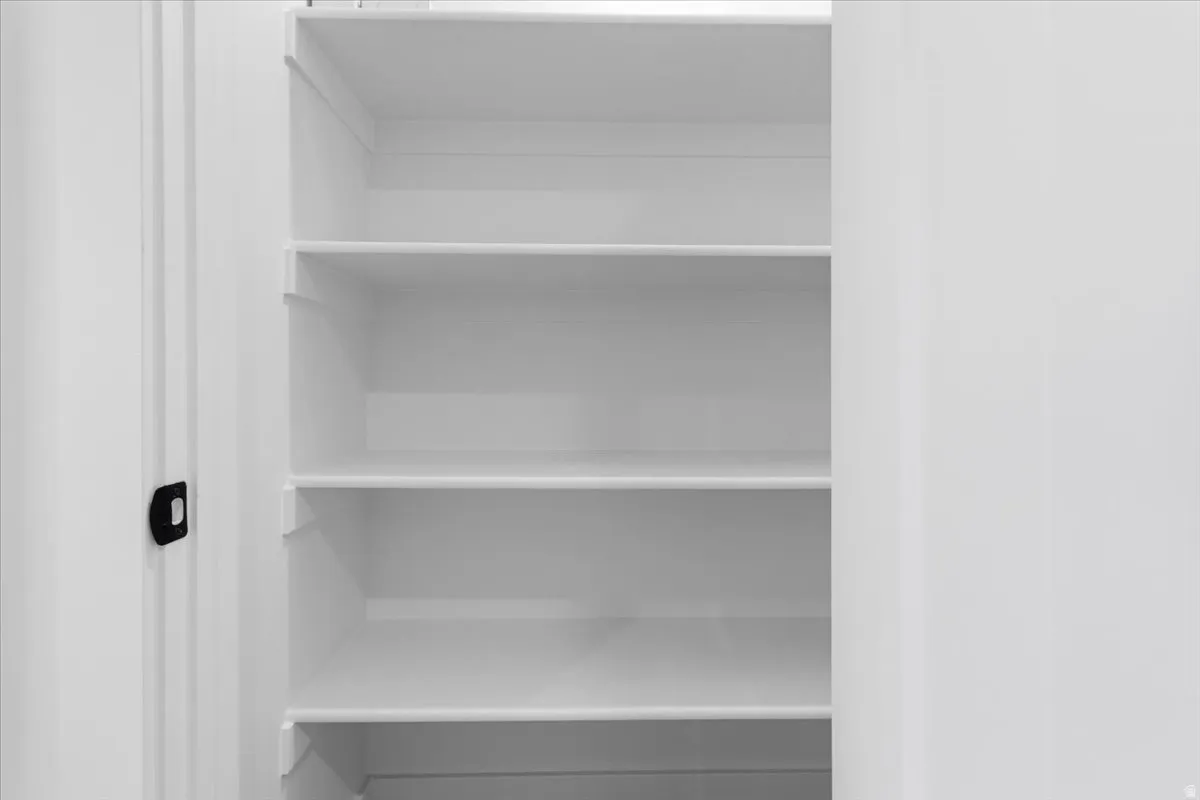 Built-in closet with five white shelves and a black door pull