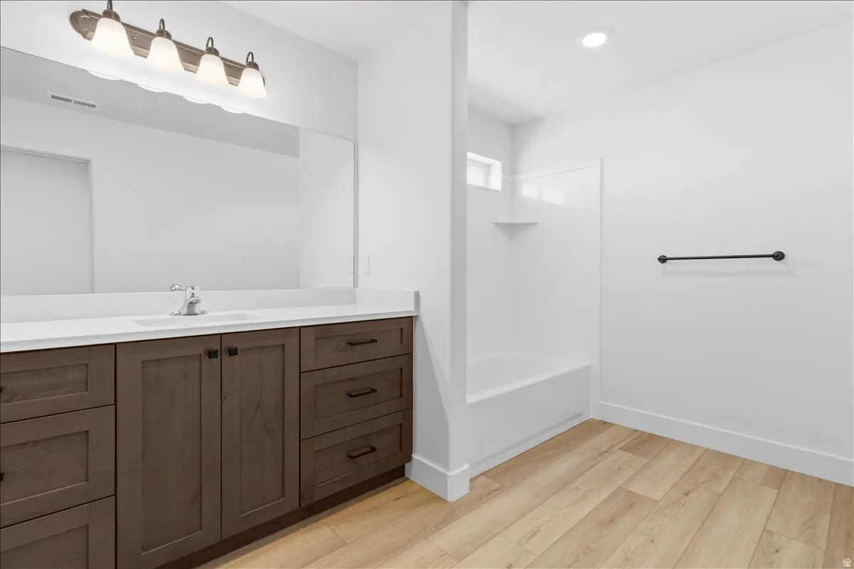 Bathroom featuring a wide wood-finish vanity with a light-toned countertop and an integrated sink
