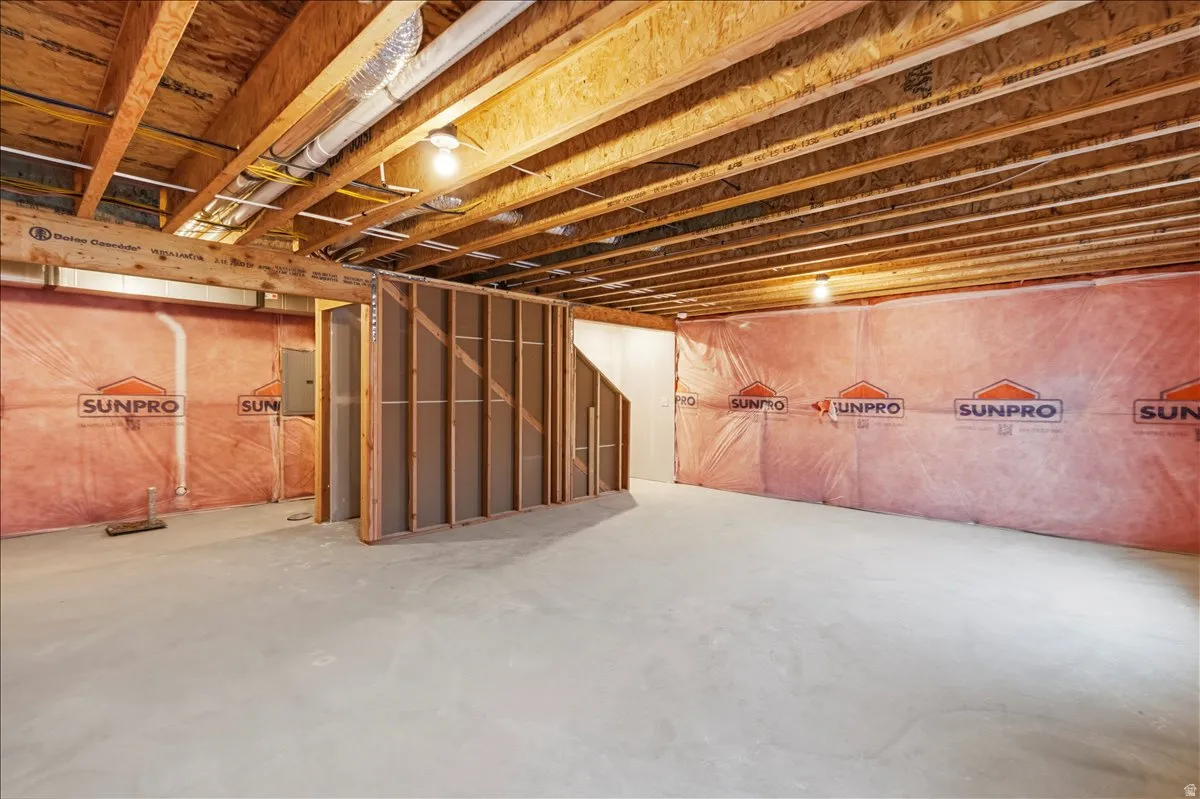 Unfinished basement featuring exposed wood joists, concrete flooring, and insulated perimeter walls