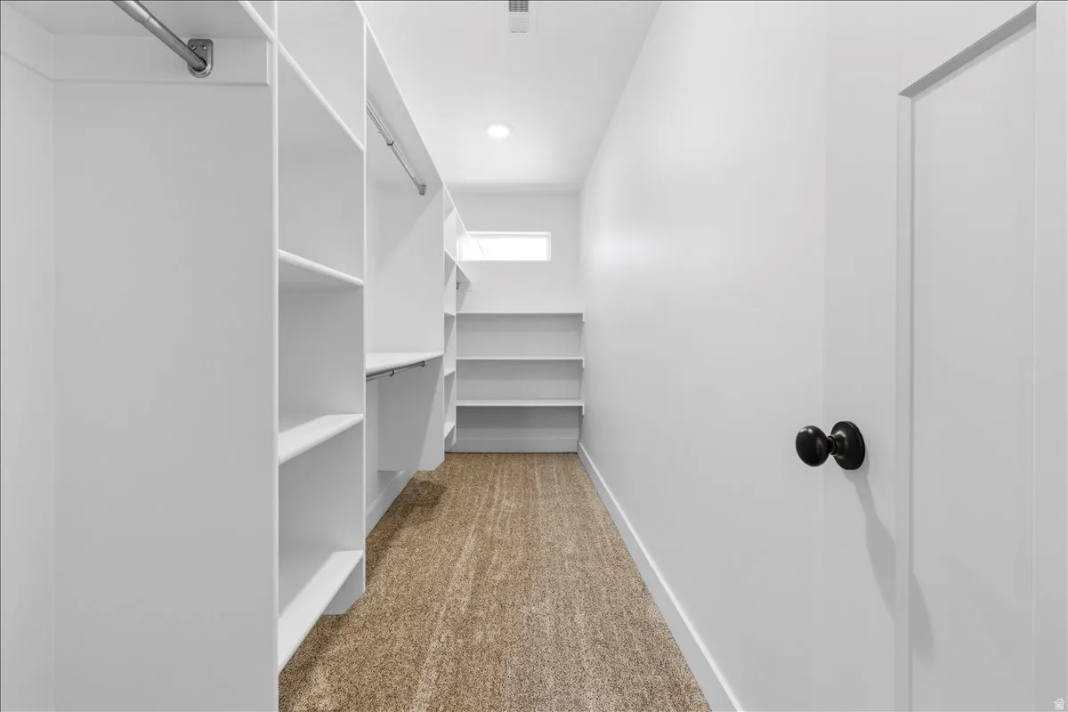 Walk-in closet featuring extensive built-in shelving, hanging rods, recessed lighting, and a window for natural illumination