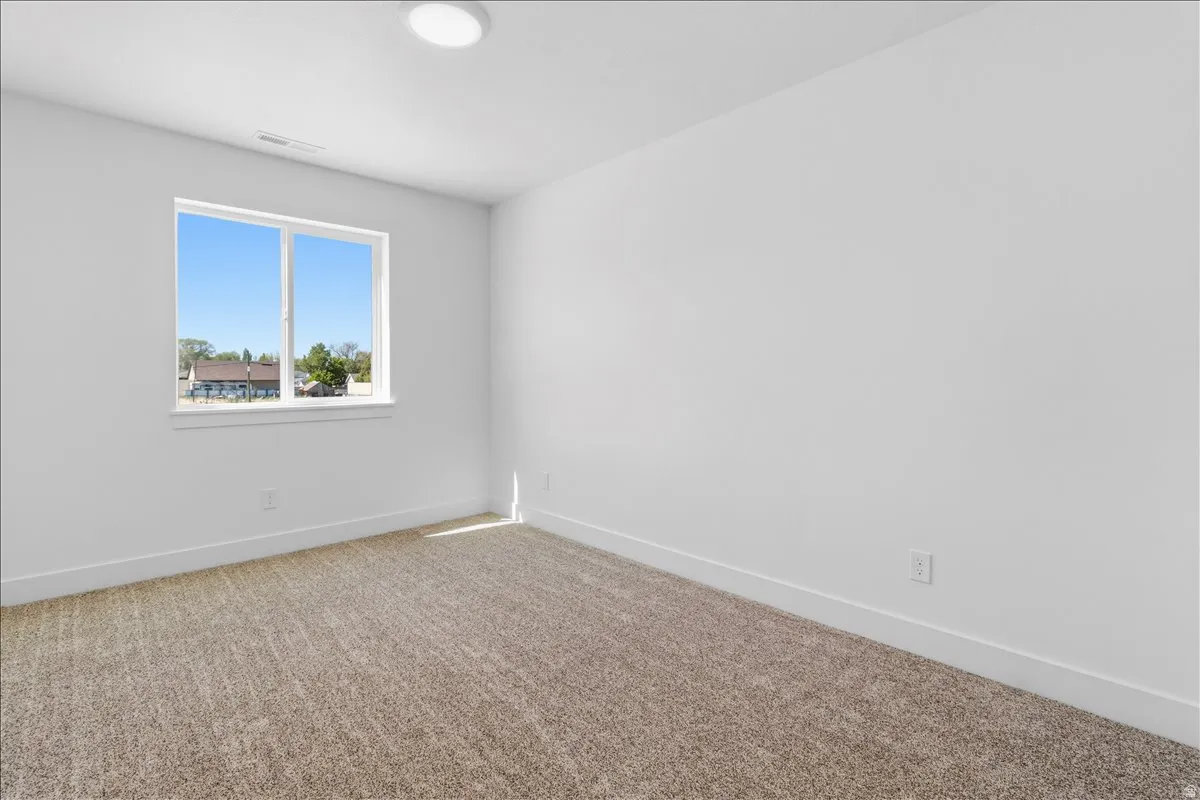 Neutral-toned carpeted flooring with white baseboards