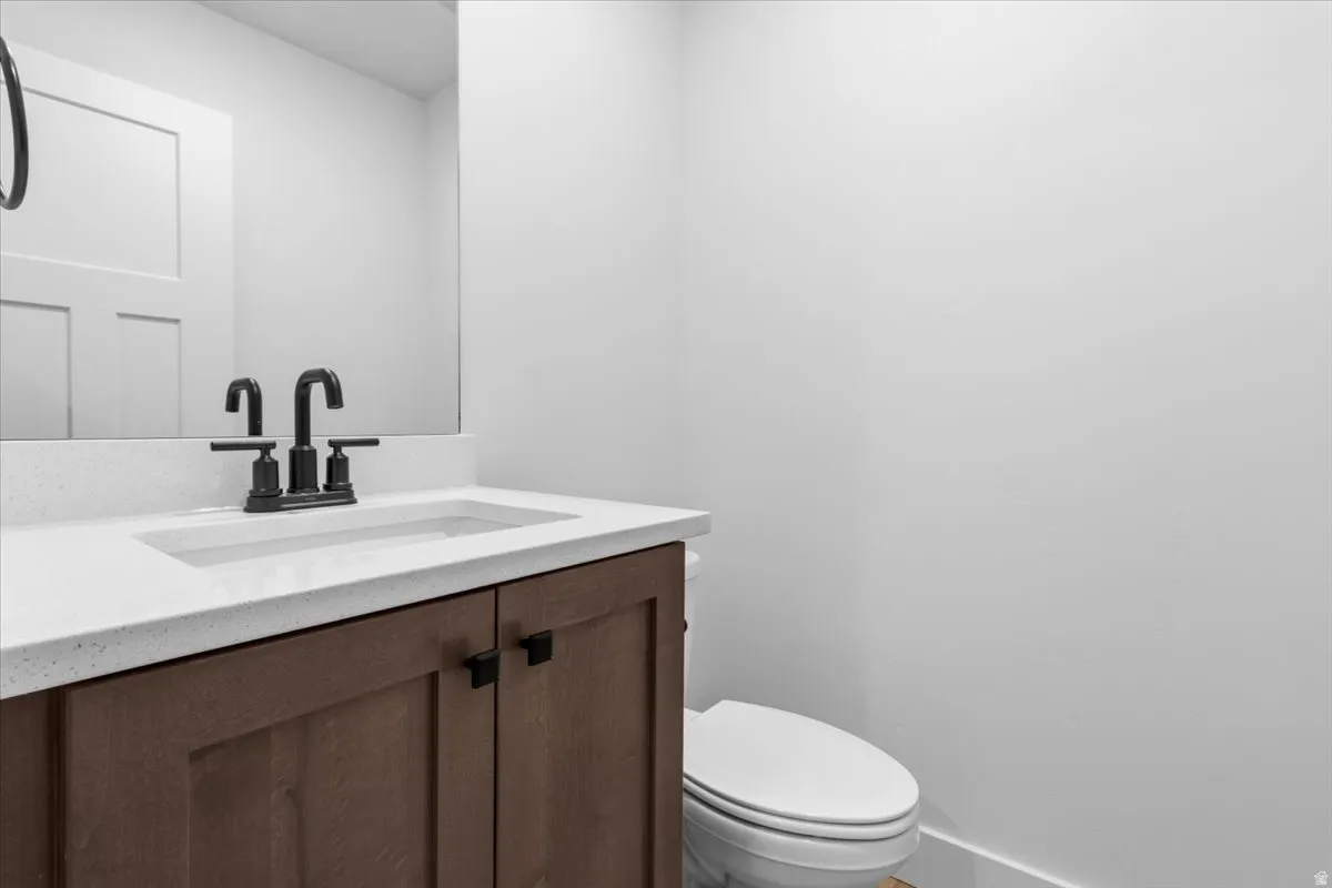 Bathroom vanity featuring a light-colored solid surface countertop, an undermount sink, and a black faucet