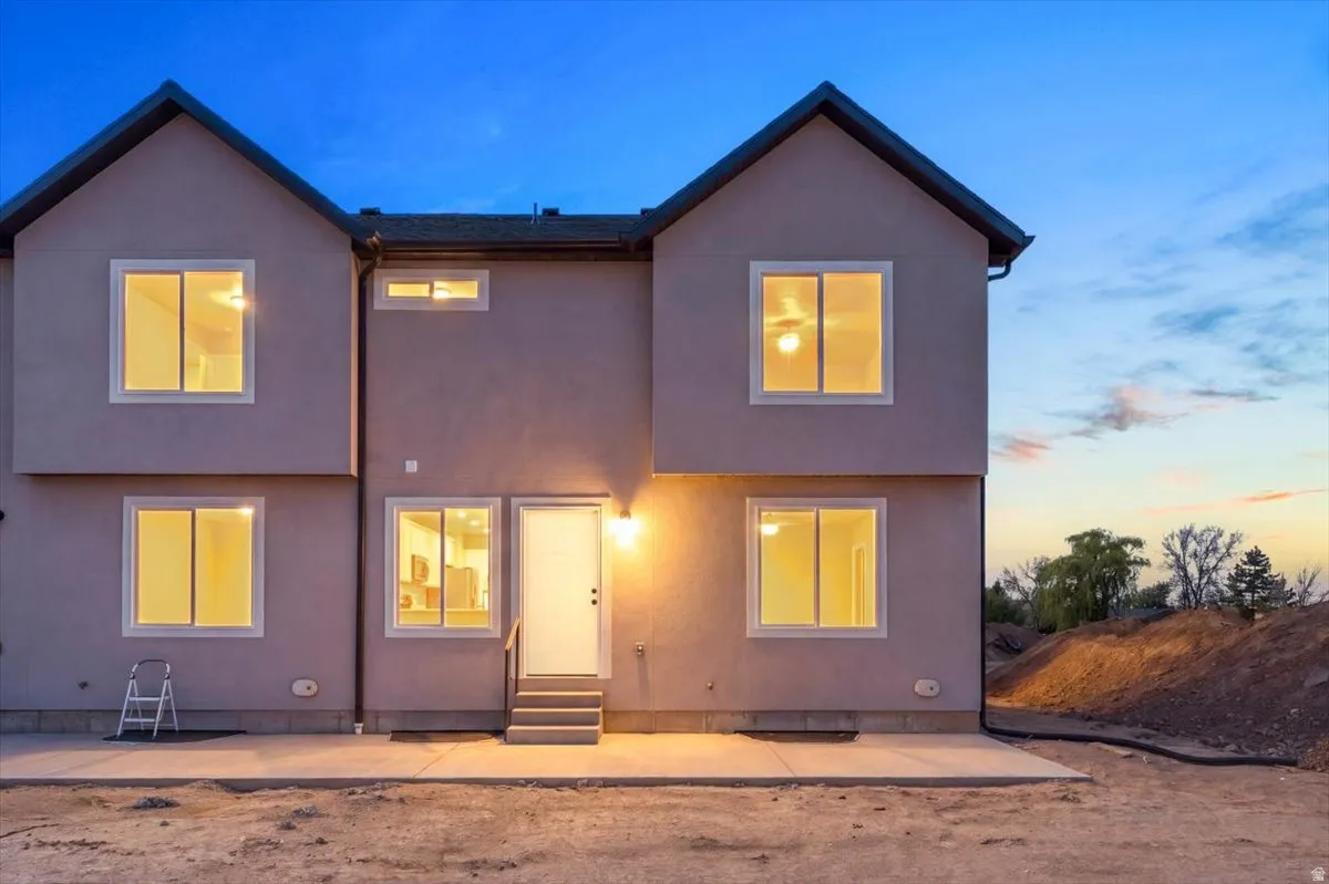 Rear exterior featuring a stucco finish, multiple large windows, and a concrete patio