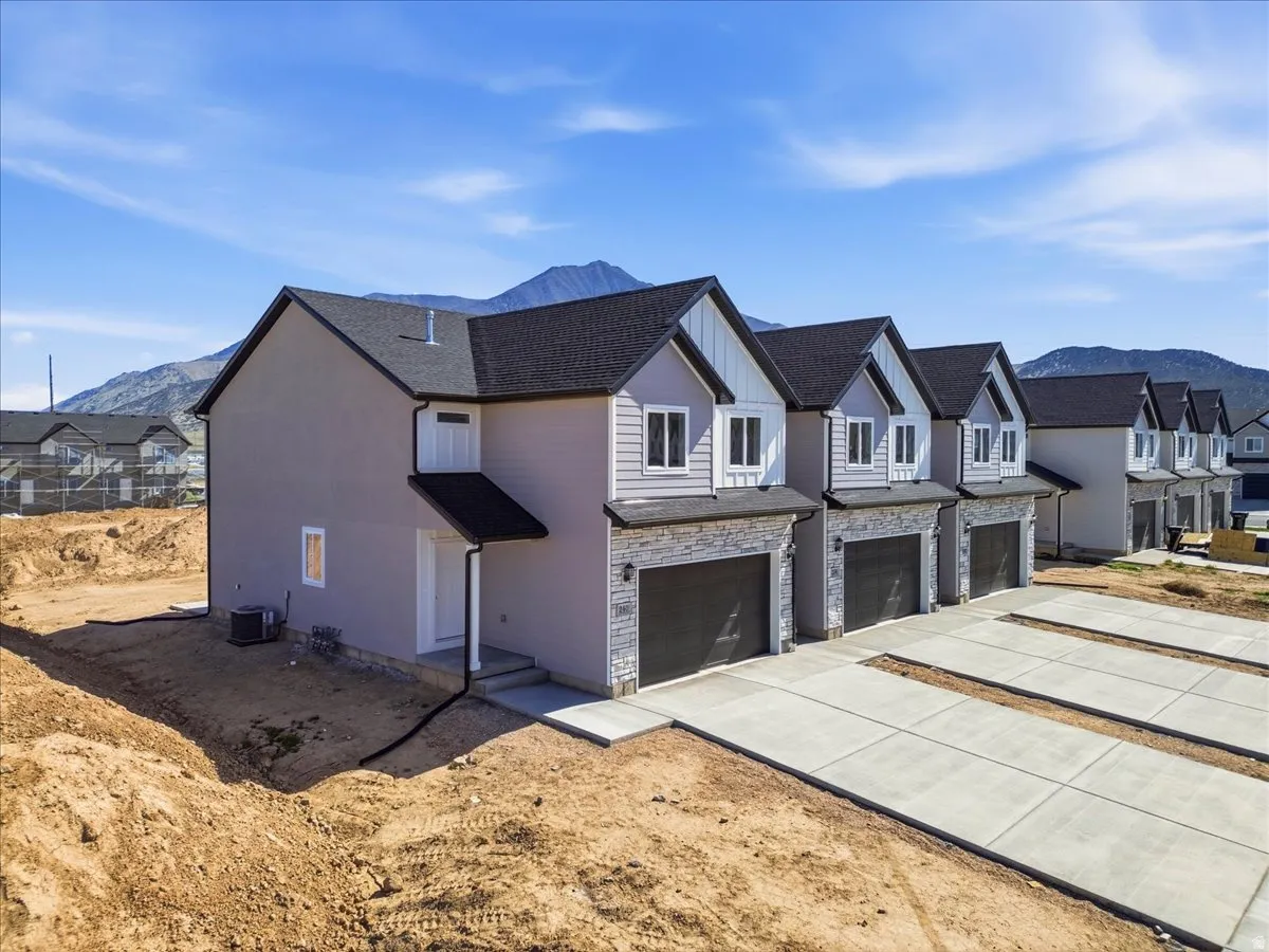 Modern townhome-style residences featuring dark shingle roofing, light-toned siding, and stone veneer accents
