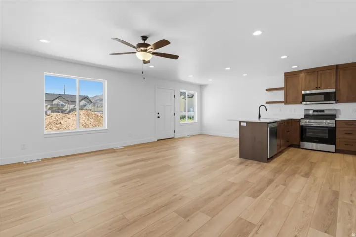 Open-concept living space featuring wood-finish flooring, recessed lighting, and a ceiling fan