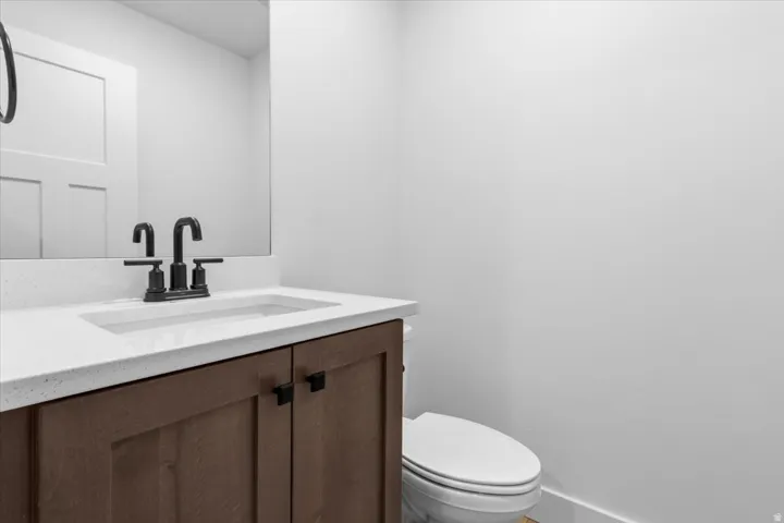 Bathroom vanity featuring a light-colored solid surface countertop, an undermount sink, and a black faucet