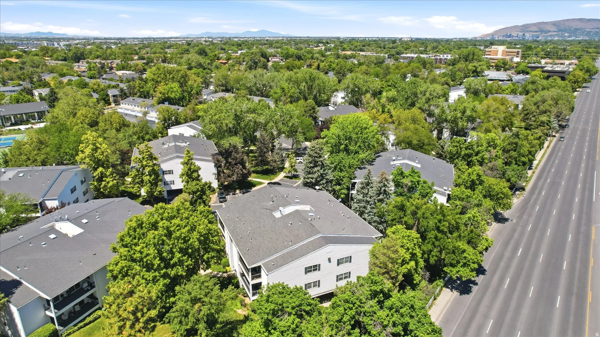 Expansive aerial showcasing multiple multi-story residential buildings surrounded by mature trees