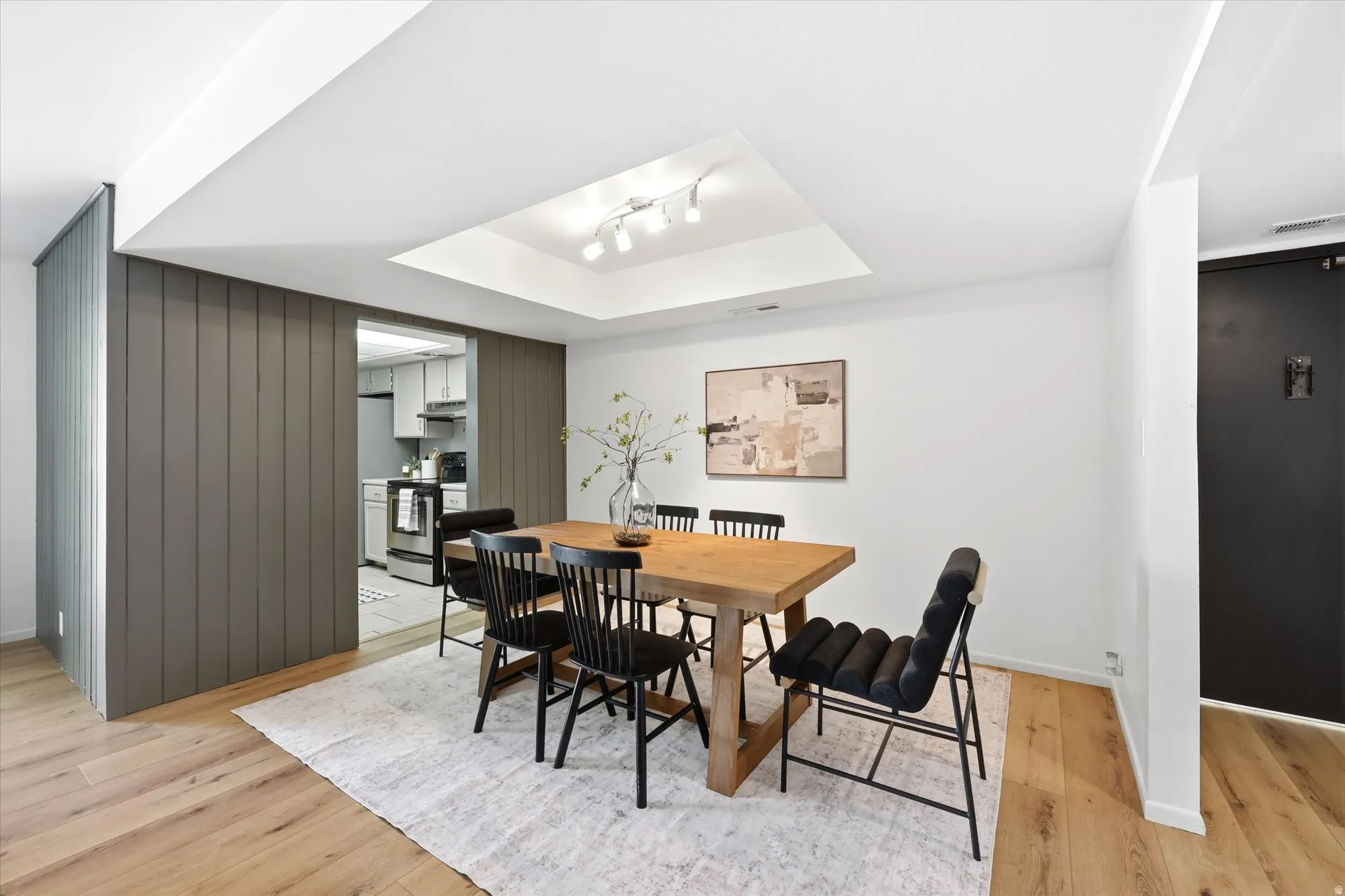 Dining area featuring wood-finish flooring, recessed lighting, and a tray ceiling with track lighting
