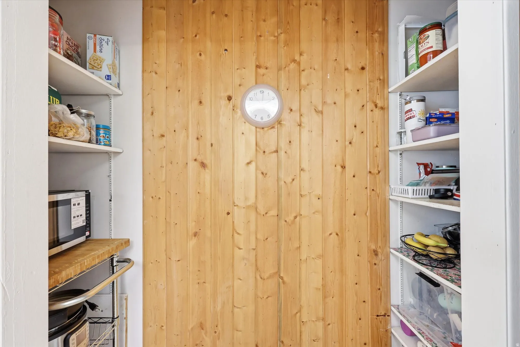 Pantry with vertical wood paneling and two walls of adjustable white shelving