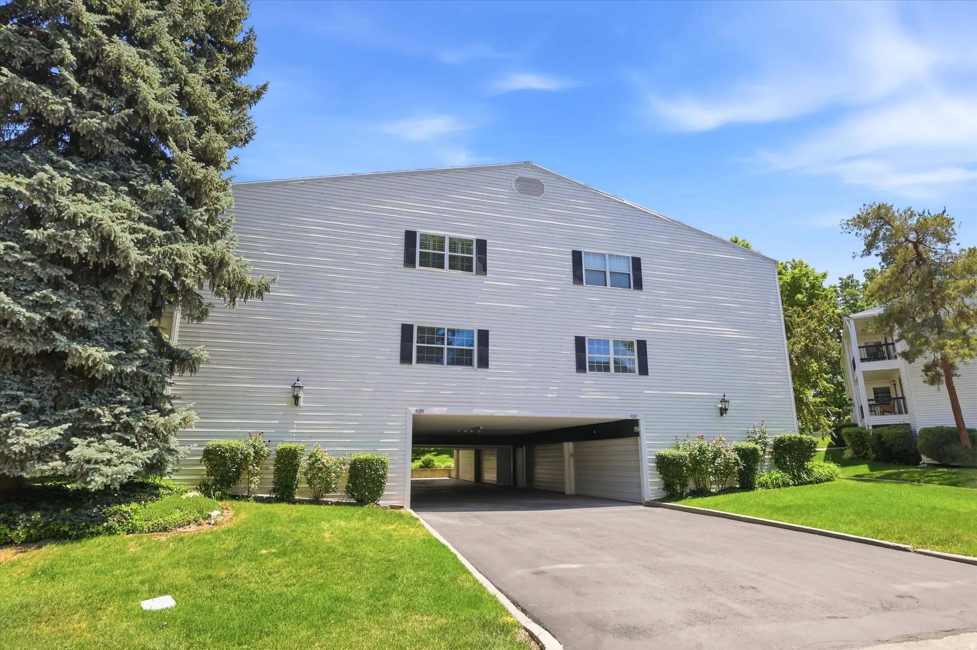 White siding exterior with multiple windows, black shutters, and wall-mounted light fixtures